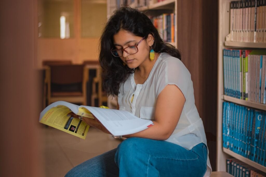 A woman reading a book in a library, creating a focused and serene atmosphere.