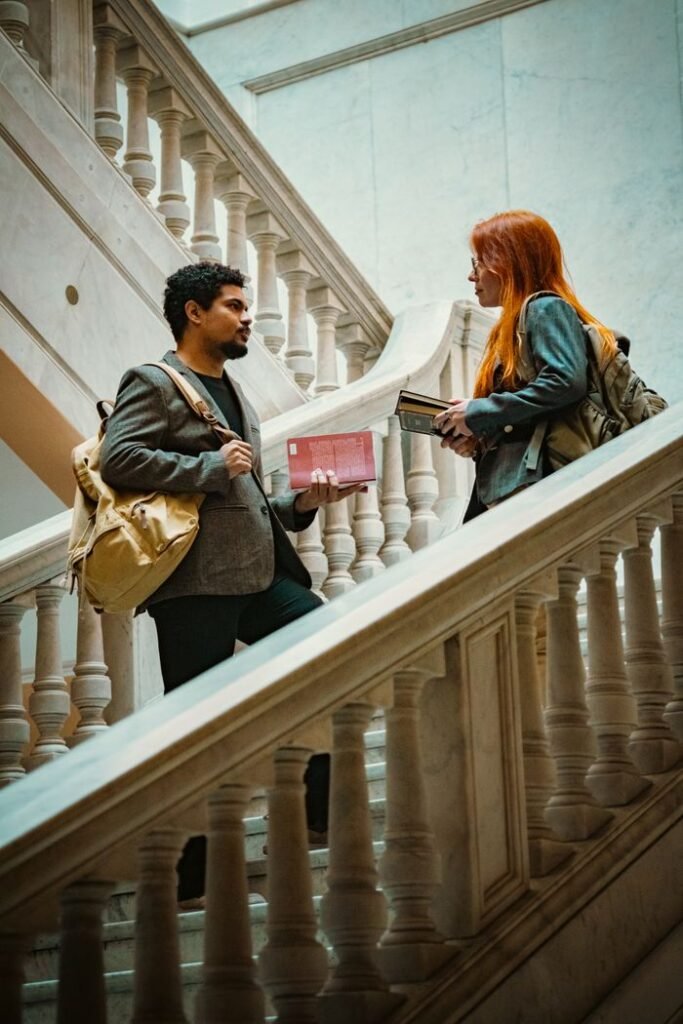Two students chatting on a marble staircase indoors at a university in Buenos Aires.